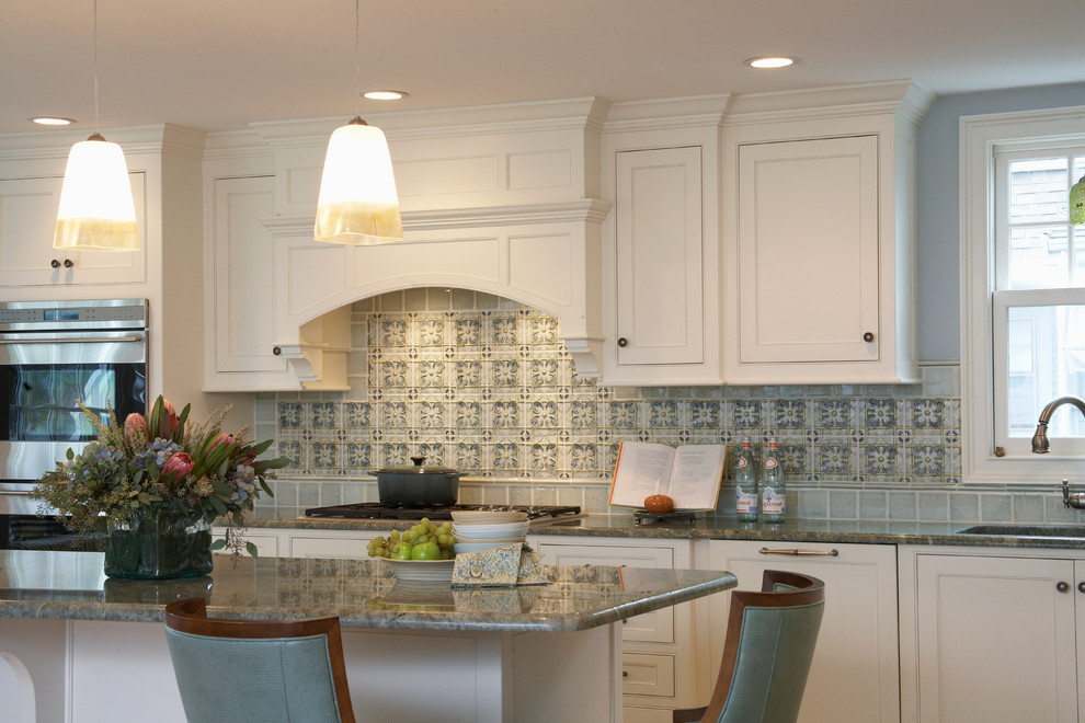 Foto de cocina clásica renovada con armarios con rebordes decorativos, puertas de armario blancas, encimera de granito, salpicadero azul, electrodomésticos de acero inoxidable y barras de cocina