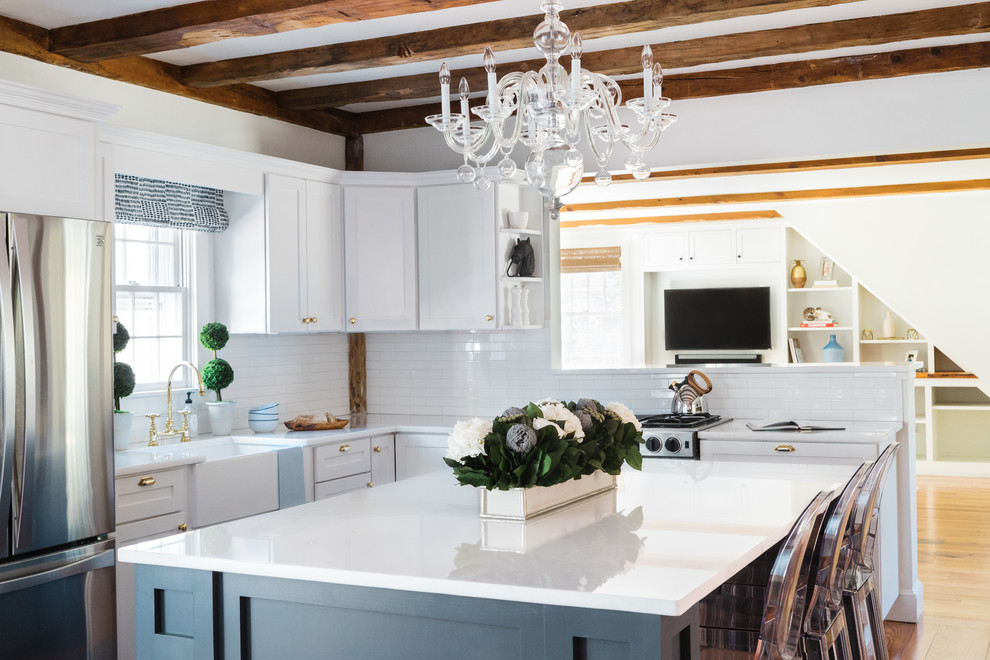 Bild på ett mellanstort maritimt kök, med en rustik diskho, skåp i shakerstil, blå skåp, marmorbänkskiva, vitt stänkskydd, stänkskydd i glaskakel, vita vitvaror, mörkt trägolv, en köksö och brunt golv