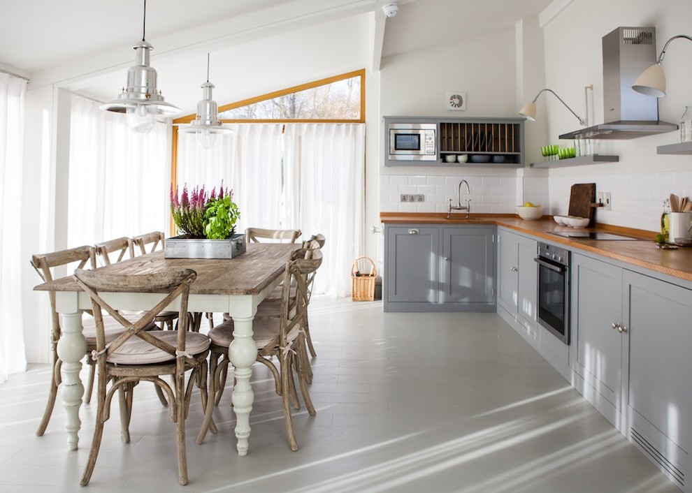 Foto på ett lantligt kök och matrum, med skåp i shakerstil, grå skåp, träbänkskiva, vitt stänkskydd, stänkskydd i keramik, rostfria vitvaror, en rustik diskho och målat trägolv