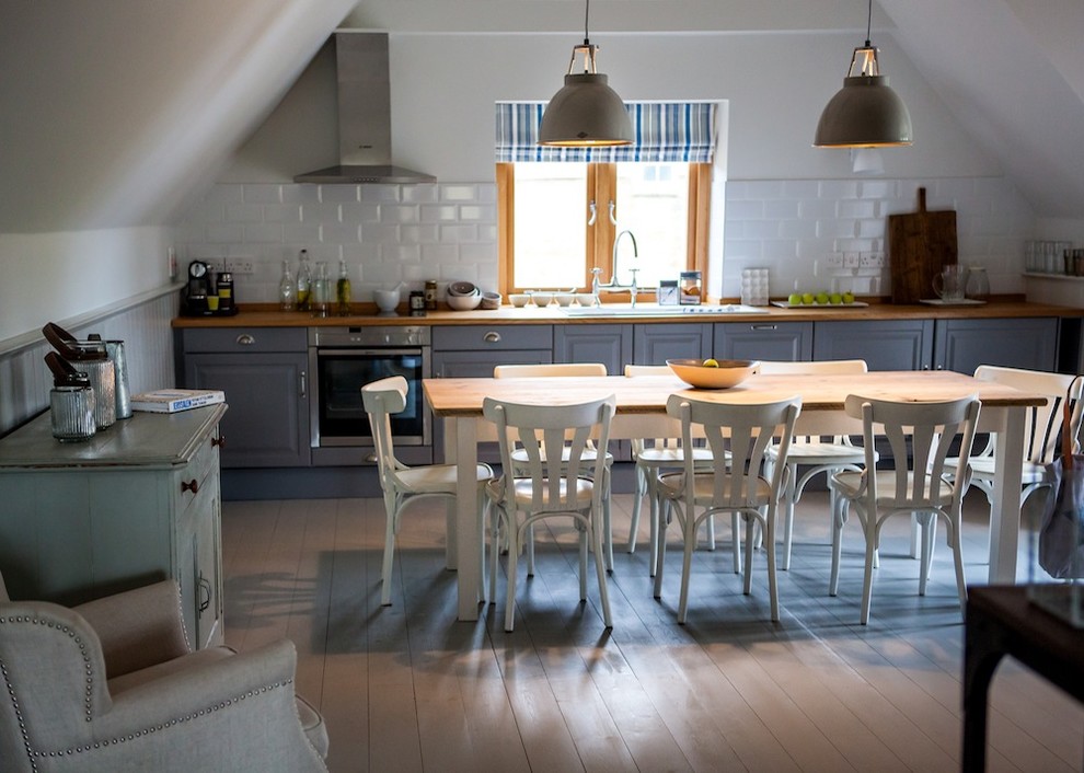 This is an example of a nautical single-wall open plan kitchen in Kent with shaker cabinets, grey cabinets, wood worktops, white splashback, ceramic splashback, stainless steel appliances, a double-bowl sink and painted wood flooring.