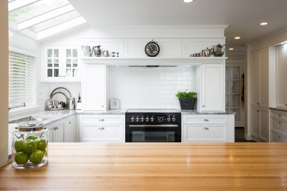 Eat-in kitchen - large traditional u-shaped dark wood floor and brown floor eat-in kitchen idea in Auckland with shaker cabinets, white cabinets, granite countertops, white backsplash, subway tile backsplash, a peninsula, an undermount sink and paneled appliances