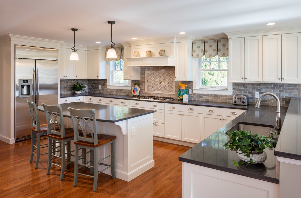 Eat-in kitchen - large coastal u-shaped medium tone wood floor and brown floor eat-in kitchen idea in Providence with an undermount sink, shaker cabinets, white cabinets, quartz countertops, gray backsplash, subway tile backsplash, stainless steel appliances and an island