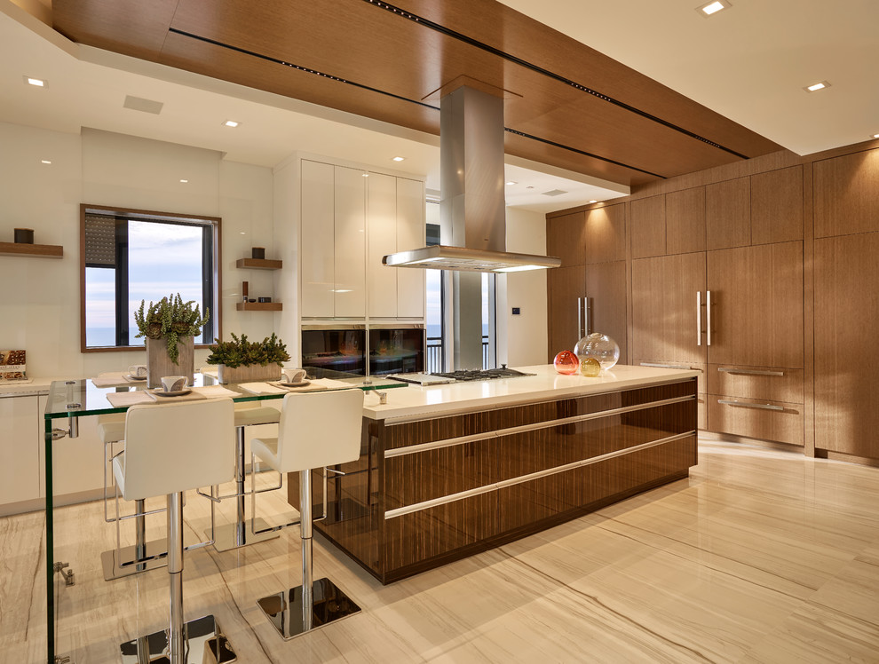 Moderne Küche mit flächenbündigen Schrankfronten, hellbraunen Holzschränken und Kücheninsel in Miami