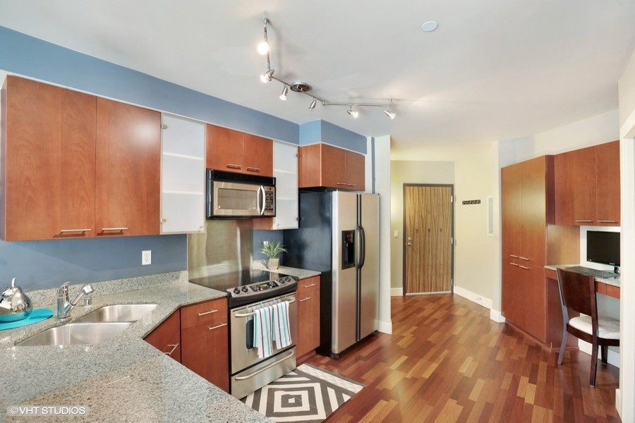 Medium sized contemporary kitchen in Seattle with a submerged sink, flat-panel cabinets, medium wood cabinets, granite worktops, stainless steel appliances, light hardwood flooring and a breakfast bar.