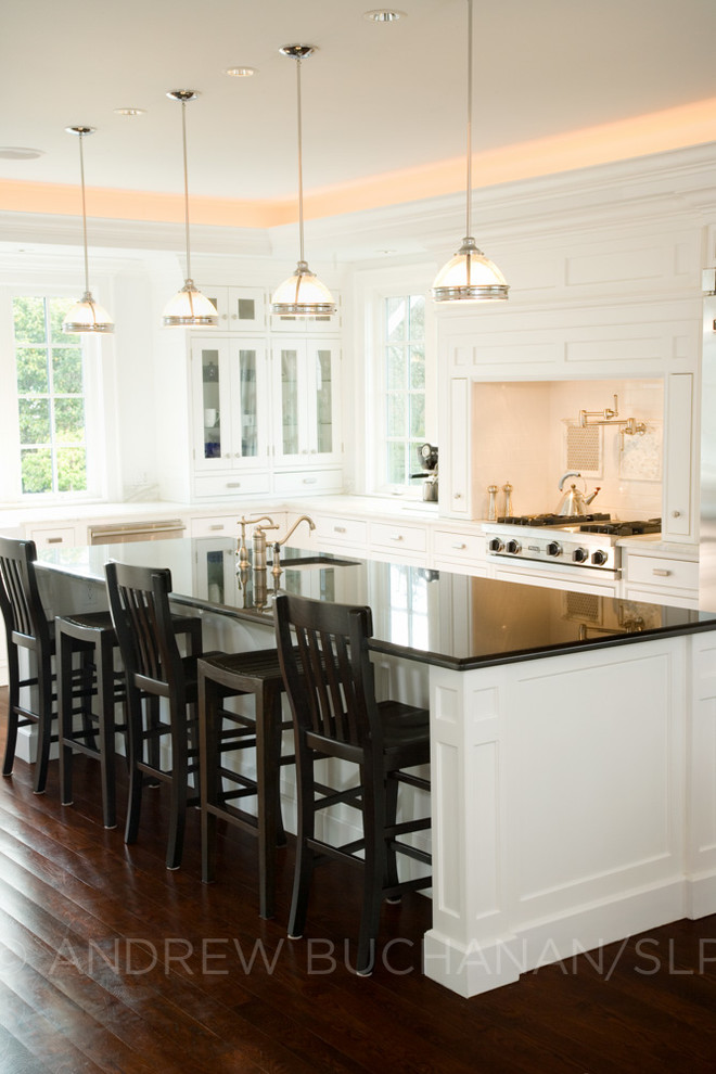 Example of a large classic single-wall dark wood floor eat-in kitchen design in Seattle with beaded inset cabinets, white cabinets, granite countertops, white backsplash, ceramic backsplash, stainless steel appliances and an island
