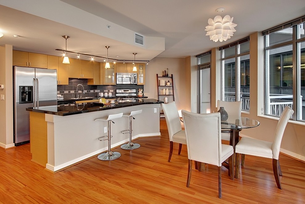 Ejemplo de cocina comedor lineal contemporánea con armarios con paneles lisos, puertas de armario de madera clara, salpicadero verde y electrodomésticos de acero inoxidable