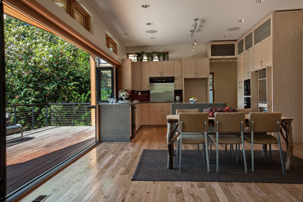 Example of a mid-sized trendy u-shaped light wood floor open concept kitchen design in Seattle with an undermount sink, flat-panel cabinets, light wood cabinets, recycled glass countertops, red backsplash, glass tile backsplash, black appliances and an island