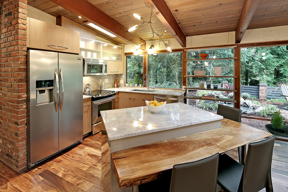 Cette image montre une petite cuisine américaine vintage en L et bois clair avec îlot, un placard à porte plane, plan de travail en marbre, une crédence multicolore, un électroménager en acier inoxydable, un évier 1 bac et un sol en bois brun.