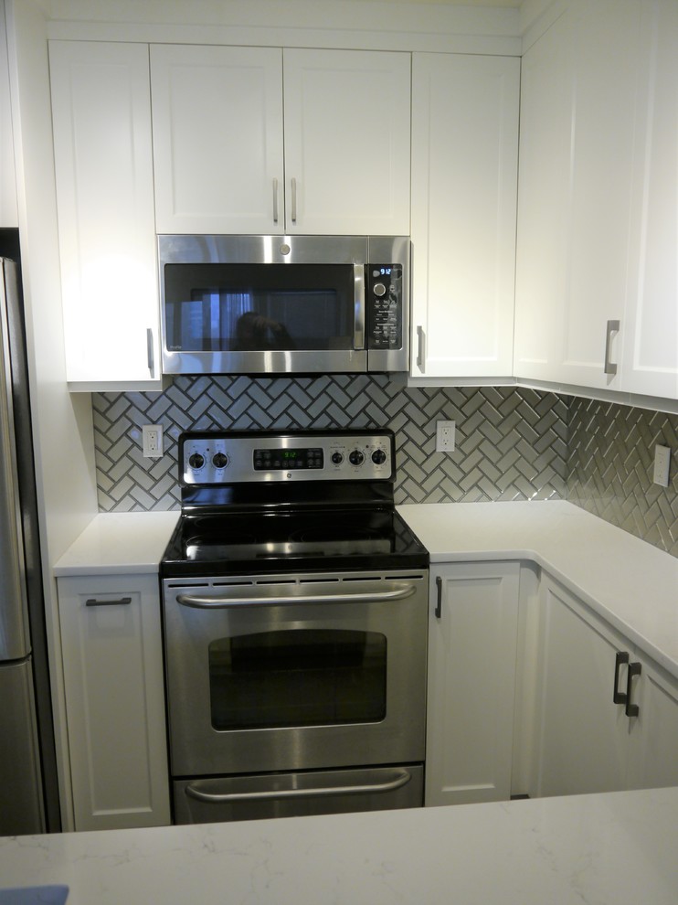 Exempel på ett litet modernt vit vitt kök, med en nedsänkt diskho, luckor med infälld panel, vita skåp, bänkskiva i kvarts, grått stänkskydd, stänkskydd i glaskakel, rostfria vitvaror, klinkergolv i porslin, en halv köksö och grått golv