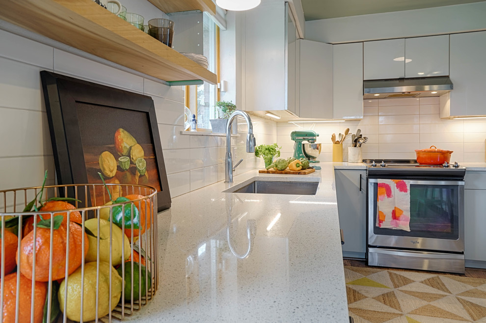 Bild på ett mellanstort funkis kök, med en undermonterad diskho, släta luckor, grå skåp, bänkskiva i kvarts, vitt stänkskydd, stänkskydd i keramik, rostfria vitvaror, laminatgolv och flerfärgat golv