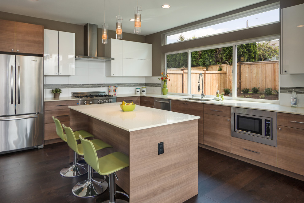 Moderne Küche in L-Form mit Unterbauwaschbecken, flächenbündigen Schrankfronten, hellbraunen Holzschränken, Küchenrückwand in Weiß, Küchengeräten aus Edelstahl, dunklem Holzboden und Kücheninsel in Seattle