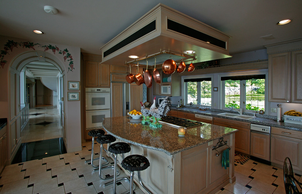 Photo of a large classic l-shaped kitchen/diner in Seattle with a built-in sink, raised-panel cabinets, light wood cabinets, granite worktops, integrated appliances, travertine flooring, an island and multi-coloured floors.
