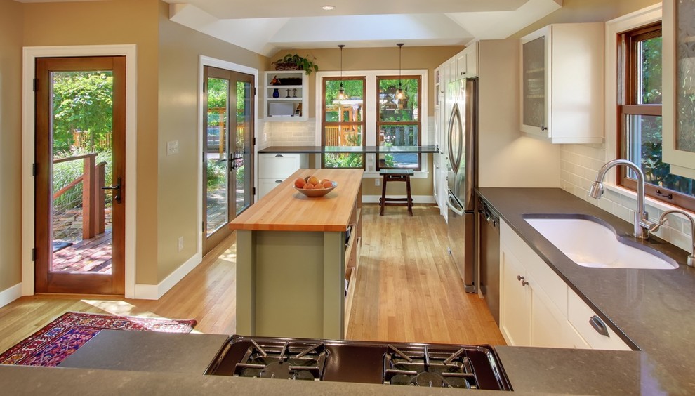 Mid-sized eclectic l-shaped light wood floor eat-in kitchen photo in Seattle with an undermount sink, shaker cabinets, white cabinets, gray backsplash, ceramic backsplash, stainless steel appliances and an island
