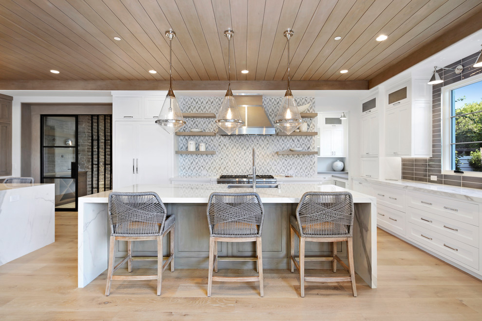Eat-in kitchen - large contemporary l-shaped light wood floor and beige floor eat-in kitchen idea in Orange County with a drop-in sink, recessed-panel cabinets, marble countertops, gray backsplash, marble backsplash, stainless steel appliances, two islands and white cabinets