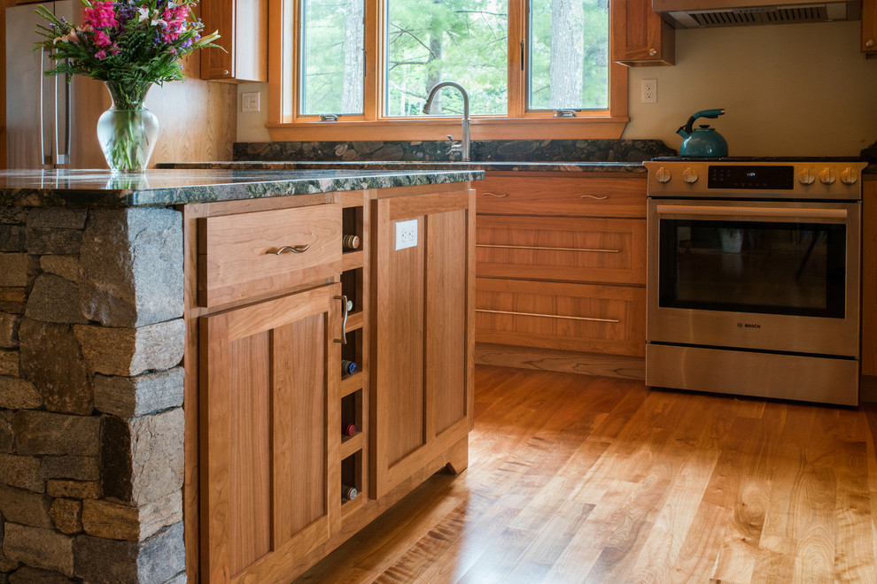 This is an example of a large classic single-wall kitchen/diner in Portland Maine with a built-in sink, shaker cabinets, medium wood cabinets, granite worktops, stainless steel appliances, light hardwood flooring and an island.