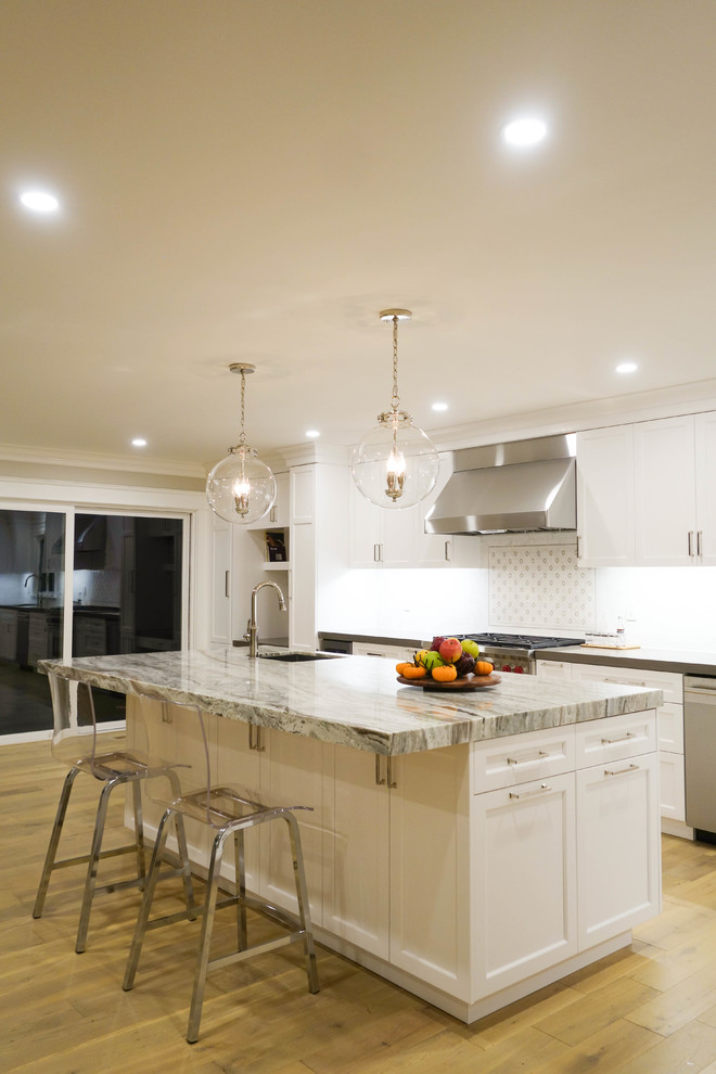 Photo of a large traditional l-shaped open plan kitchen in San Francisco with a single-bowl sink, recessed-panel cabinets, white cabinets, granite worktops, white splashback, marble splashback, stainless steel appliances, medium hardwood flooring, an island and brown floors.