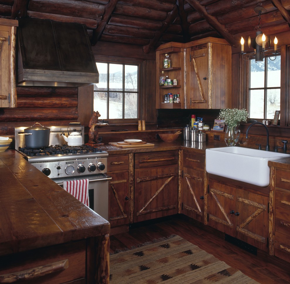Inspiration för små rustika brunt u-kök, med en rustik diskho, träbänkskiva, stänkskydd i trä, mellanmörkt trägolv, skåp i mellenmörkt trä, brunt stänkskydd, rostfria vitvaror, en halv köksö och brunt golv