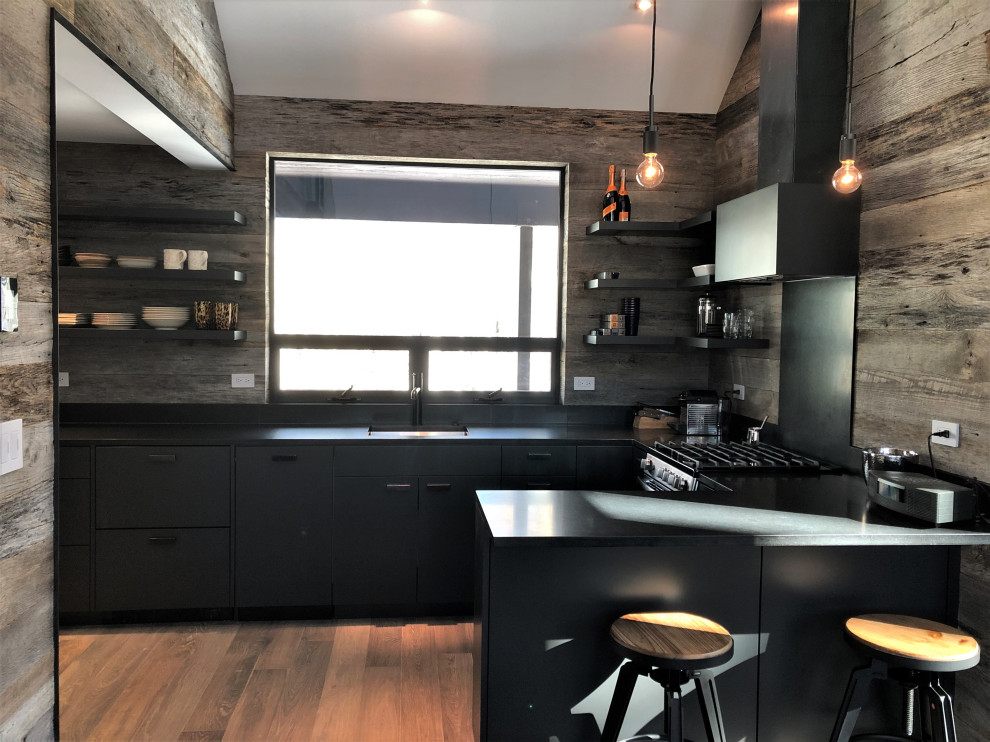 Inspiration for a mid-sized contemporary u-shaped light wood floor, orange floor and vaulted ceiling open concept kitchen remodel in Other with an undermount sink, flat-panel cabinets, black cabinets, brown backsplash, stainless steel appliances, a peninsula and brown countertops