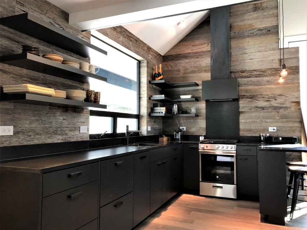 Open concept kitchen - mid-sized contemporary u-shaped light wood floor, orange floor and vaulted ceiling open concept kitchen idea in Other with an undermount sink, flat-panel cabinets, black cabinets, brown backsplash, stainless steel appliances, a peninsula and brown countertops