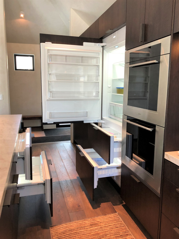 Large trendy galley medium tone wood floor, brown floor and vaulted ceiling open concept kitchen photo in Other with an undermount sink, flat-panel cabinets, dark wood cabinets, colored appliances, an island and multicolored countertops