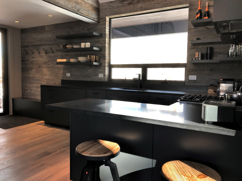 Open concept kitchen - mid-sized contemporary u-shaped light wood floor, orange floor and vaulted ceiling open concept kitchen idea in Other with an undermount sink, flat-panel cabinets, black cabinets, brown backsplash, stainless steel appliances, a peninsula and brown countertops