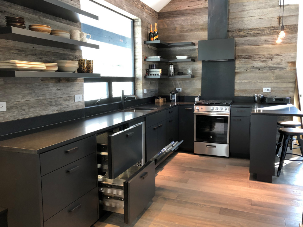 Example of a mid-sized trendy u-shaped light wood floor, orange floor and vaulted ceiling open concept kitchen design in Other with an undermount sink, flat-panel cabinets, black cabinets, brown backsplash, stainless steel appliances, a peninsula and brown countertops