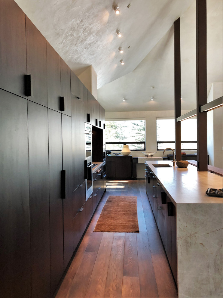 Inspiration for a large contemporary galley medium tone wood floor, brown floor and vaulted ceiling open concept kitchen remodel in Other with an undermount sink, flat-panel cabinets, dark wood cabinets, colored appliances, an island and multicolored countertops