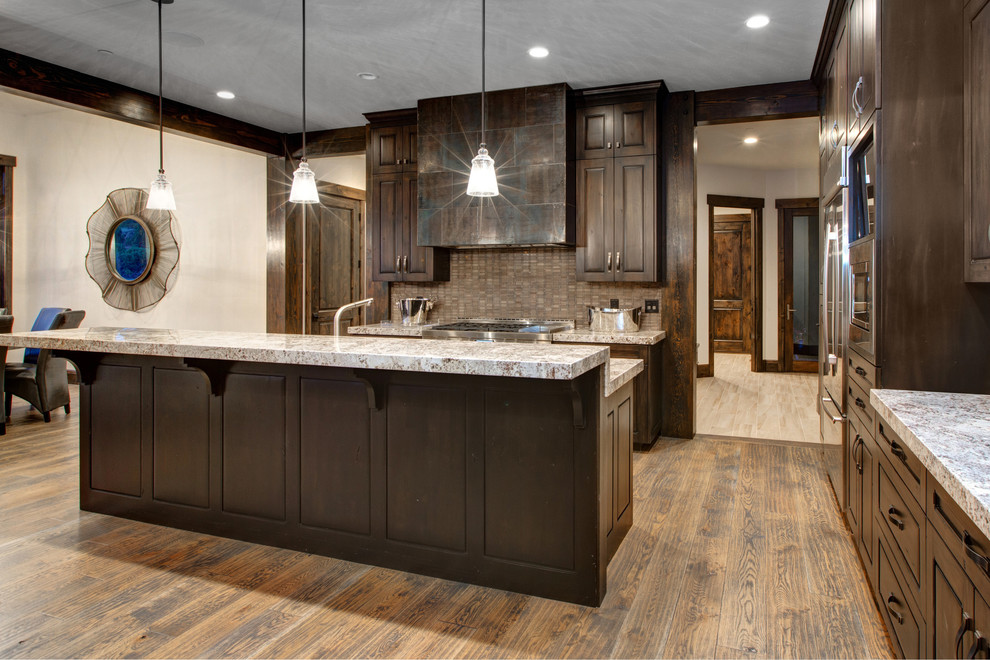 Example of a large mountain style l-shaped medium tone wood floor open concept kitchen design in Salt Lake City with a drop-in sink, recessed-panel cabinets, dark wood cabinets, marble countertops, gray backsplash, glass tile backsplash, stainless steel appliances and an island