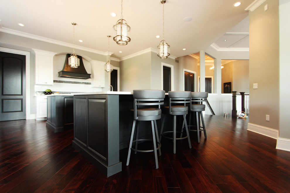 Huge transitional l-shaped dark wood floor open concept kitchen photo in Other with a double-bowl sink, raised-panel cabinets, white cabinets, quartz countertops, white backsplash, porcelain backsplash, paneled appliances and two islands