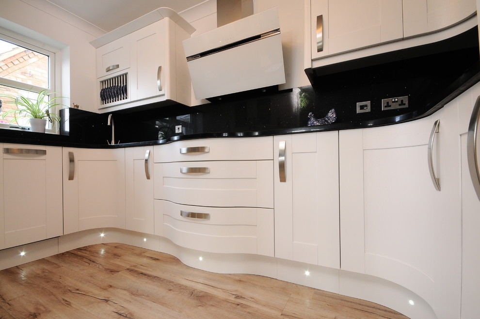 This is an example of a small contemporary u-shaped kitchen/diner in Other with an integrated sink, shaker cabinets, white cabinets, composite countertops, black splashback, stainless steel appliances, lino flooring and no island.