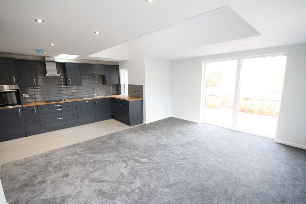 Medium sized modern single-wall open plan kitchen in Edinburgh with blue cabinets, grey splashback and brown worktops.