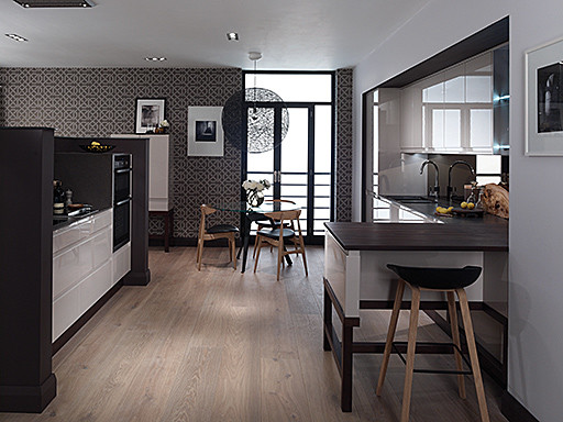 Design ideas for a medium sized contemporary galley kitchen/diner in Surrey with white cabinets, wood worktops, stainless steel appliances and a breakfast bar.