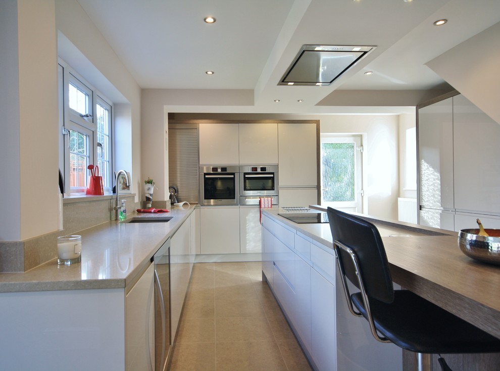 Photo of a large modern kitchen/diner in Essex with a belfast sink, flat-panel cabinets, quartz worktops, stainless steel appliances and an island.