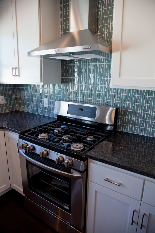 Photo of a medium sized classic kitchen/diner in Minneapolis with a submerged sink, shaker cabinets, white cabinets, granite worktops, blue splashback, glass tiled splashback, stainless steel appliances, dark hardwood flooring and an island.