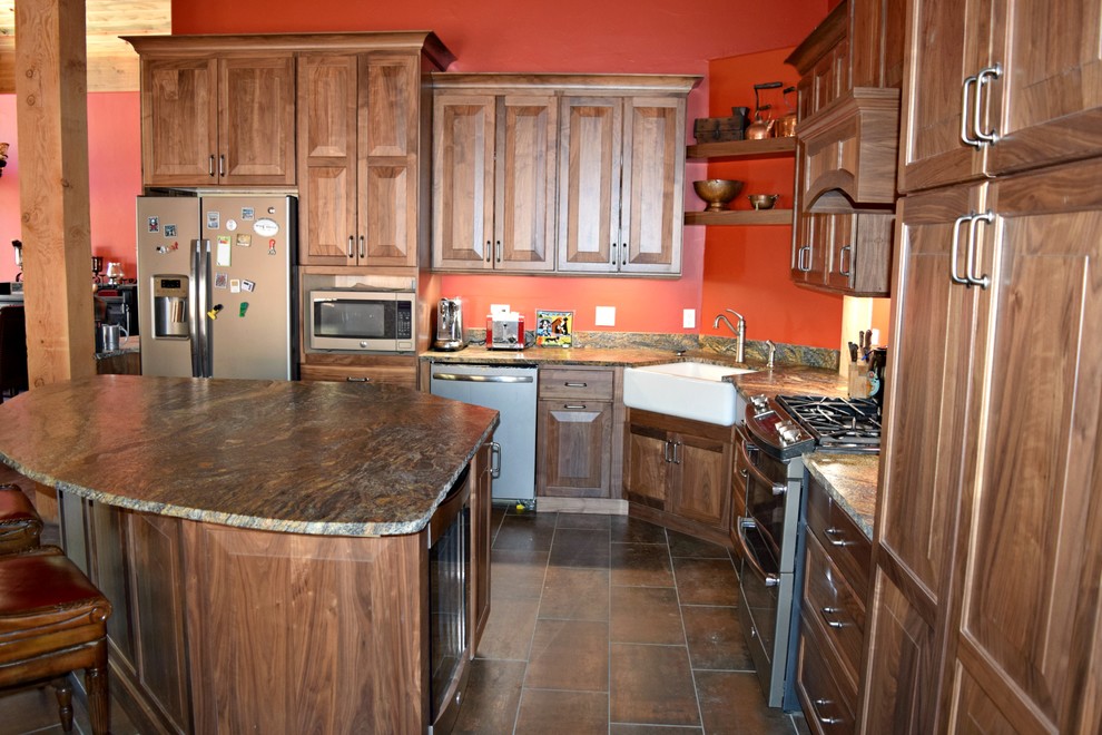 Inredning av ett rustikt stort kök, med en rustik diskho, luckor med upphöjd panel, skåp i mellenmörkt trä, granitbänkskiva, stänkskydd i sten, rostfria vitvaror och en köksö