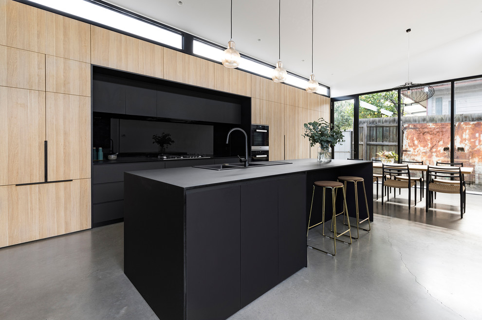 Идея дизайна: параллельная кухня в стиле модернизм с обеденным столом, двойной мойкой, плоскими фасадами, светлыми деревянными фасадами, бетонным полом, островом, серым полом и серой столешницей
