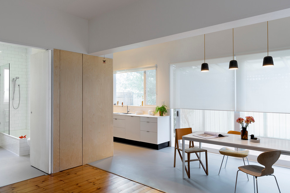 Idéer för att renovera ett litet minimalistiskt kök, med en nedsänkt diskho, vita skåp, bänkskiva i kvartsit, svart stänkskydd, spegel som stänkskydd, rostfria vitvaror och linoleumgolv