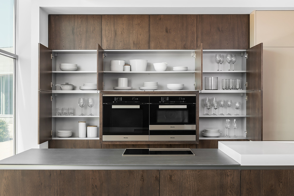 Modelo de cocina lineal minimalista grande abierta con armarios con paneles lisos, puertas de armario de madera en tonos medios, electrodomésticos de acero inoxidable y una isla