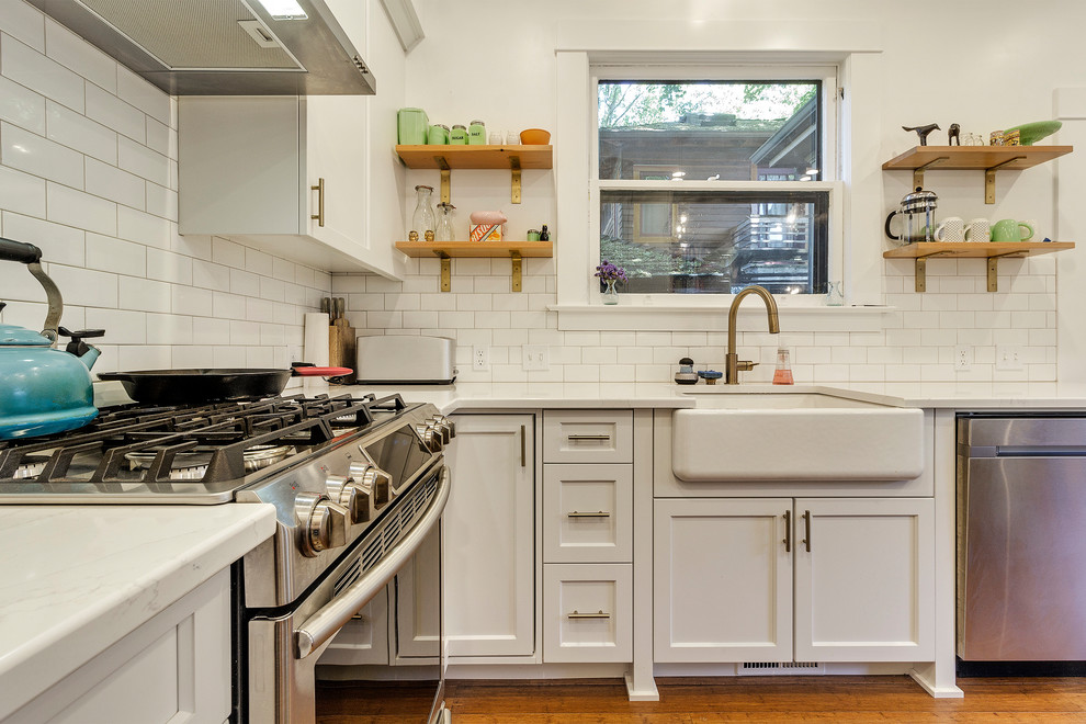 ポートランドにあるお手頃価格の広いトラディショナルスタイルのおしゃれなキッチン (エプロンフロントシンク、シェーカースタイル扉のキャビネット、白いキャビネット、クオーツストーンカウンター、白いキッチンパネル、磁器タイルのキッチンパネル、シルバーの調理設備、竹フローリング、茶色い床、白いキッチンカウンター) の写真