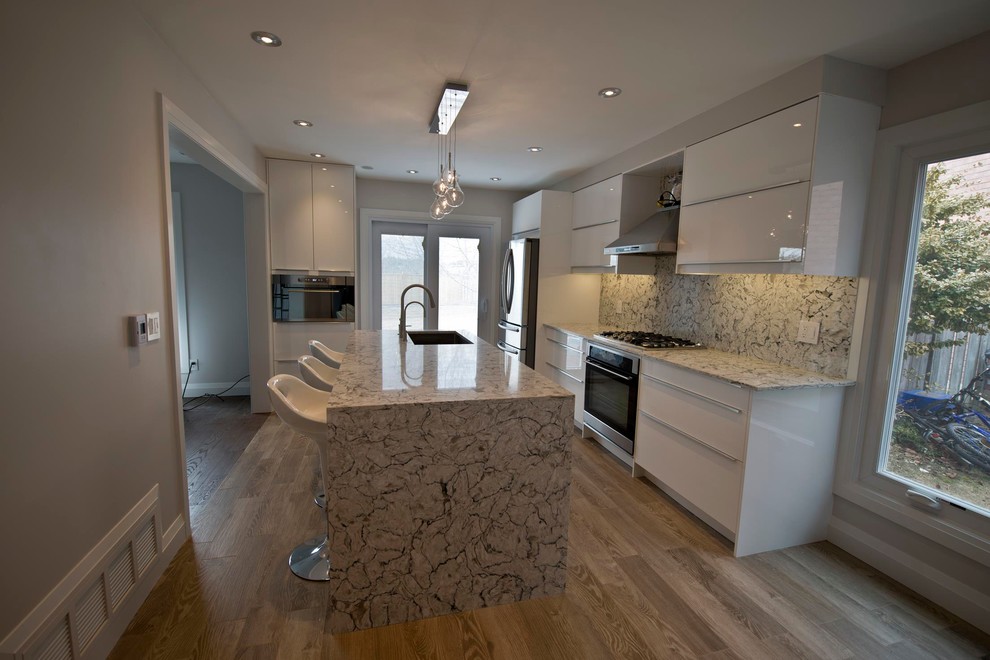 Example of a mid-sized minimalist medium tone wood floor eat-in kitchen design in Toronto with an undermount sink, flat-panel cabinets, white cabinets, quartz countertops, stone slab backsplash and stainless steel appliances
