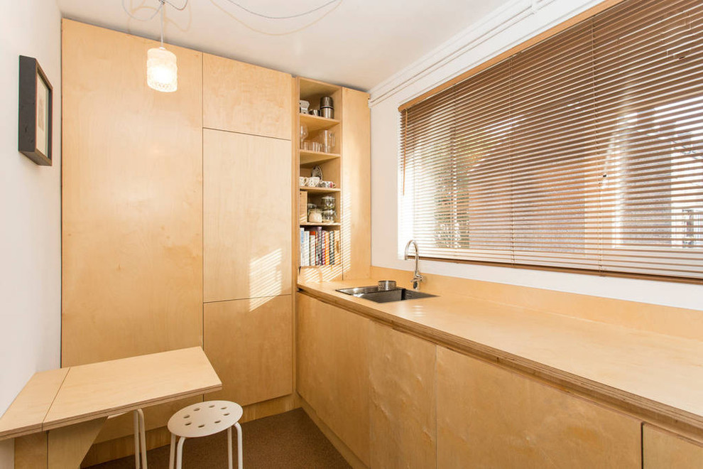 This is an example of a small scandinavian single-wall enclosed kitchen in London with a double-bowl sink, flat-panel cabinets, medium wood cabinets, wood worktops and no island.