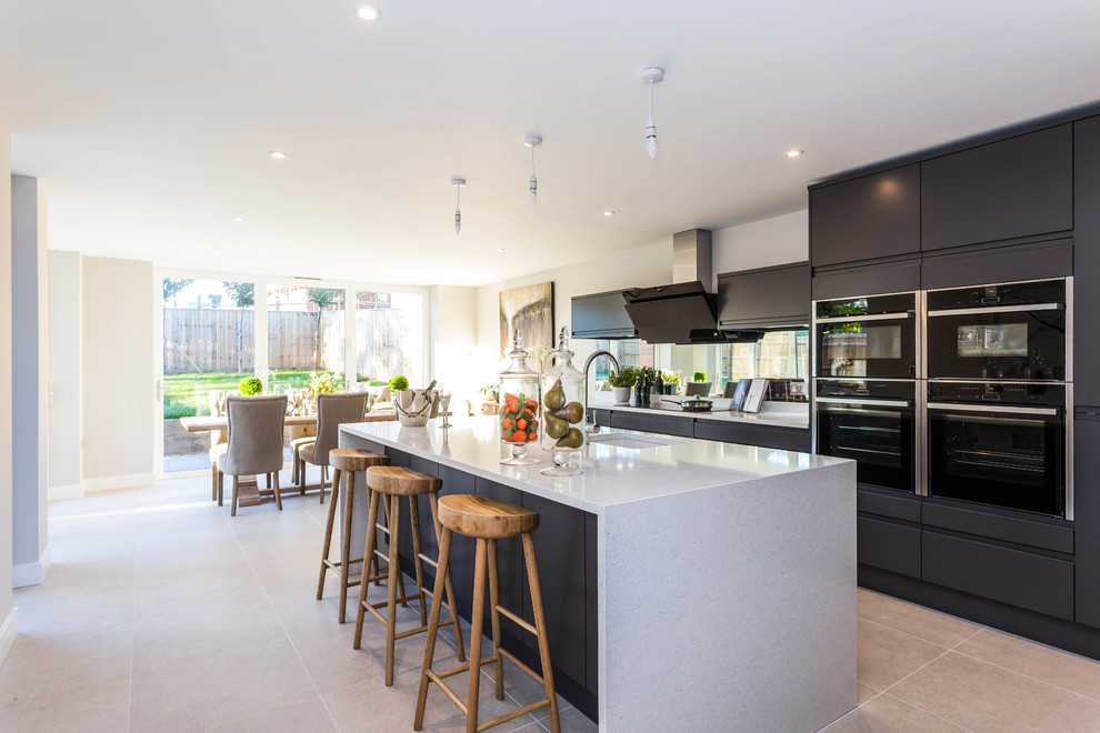This is an example of a medium sized contemporary kitchen/diner in Buckinghamshire with flat-panel cabinets, marble worktops, black appliances, ceramic flooring, an island, grey worktops, a submerged sink, black cabinets, window splashback and grey floors.