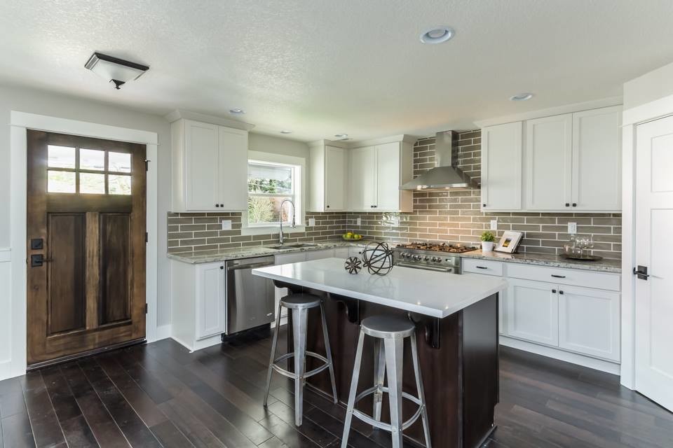 Inspiration for a mid-sized transitional l-shaped dark wood floor and brown floor eat-in kitchen remodel in Portland with shaker cabinets, white cabinets, granite countertops, subway tile backsplash, stainless steel appliances, an island, beige countertops, a double-bowl sink and beige backsplash