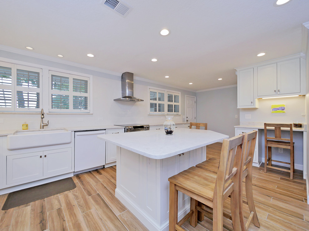 Large beach style u-shaped porcelain tile and multicolored floor kitchen photo in Jacksonville with a farmhouse sink, recessed-panel cabinets, white cabinets, quartz countertops, white backsplash, subway tile backsplash and stainless steel appliances