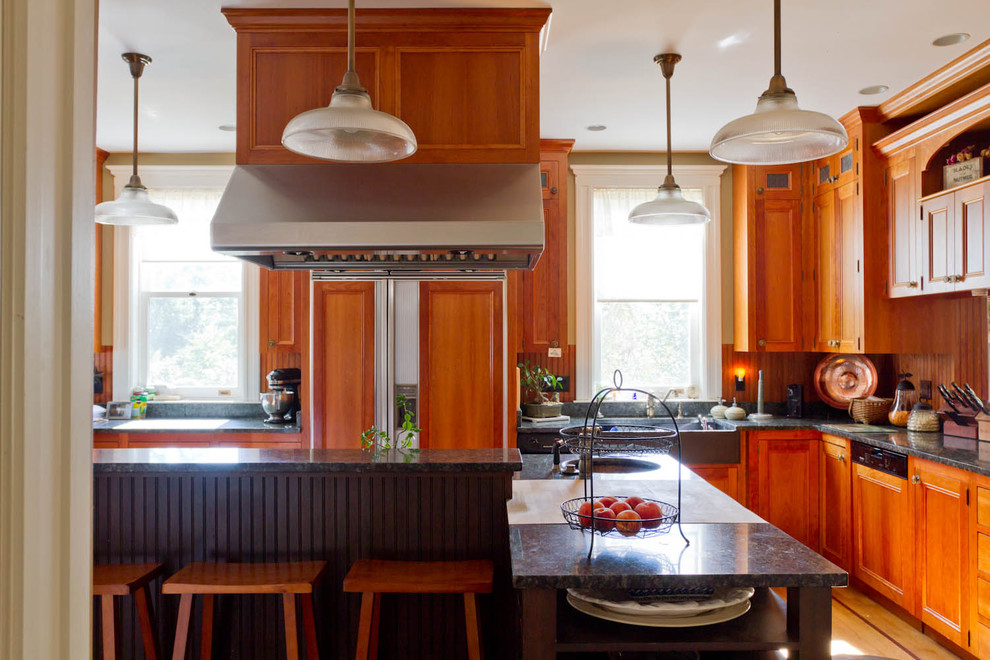 На фото: отдельная кухня в классическом стиле с с полувстраиваемой мойкой (с передним бортиком), фасадами с утопленной филенкой, фасадами цвета дерева среднего тона, гранитной столешницей и техникой под мебельный фасад