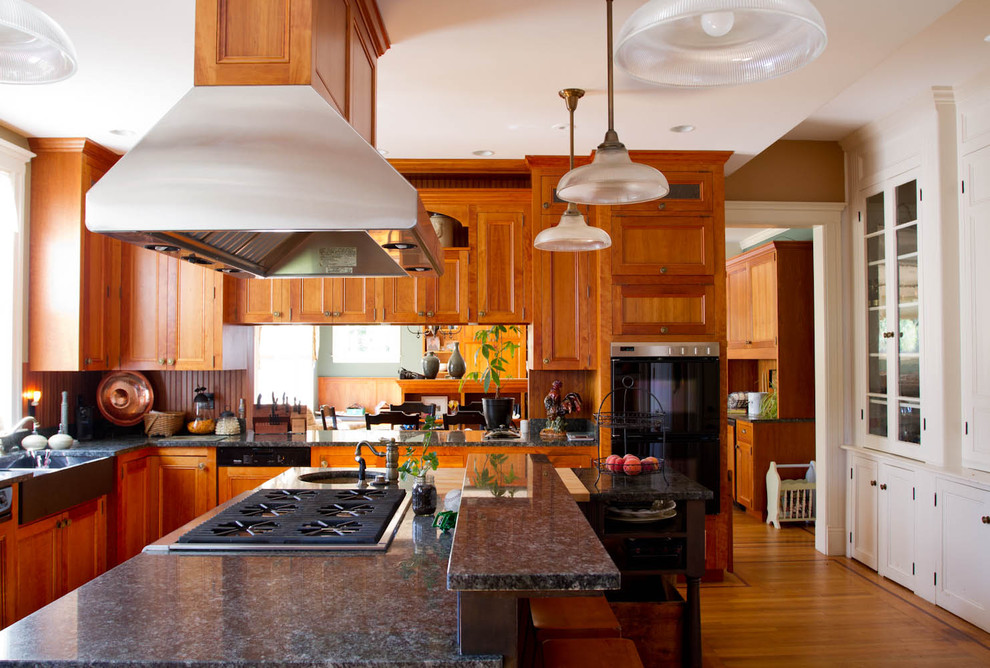 Geschlossene Klassische Küche mit Landhausspüle, Schrankfronten mit vertiefter Füllung, hellbraunen Holzschränken, Granit-Arbeitsplatte und schwarzen Elektrogeräten in New York