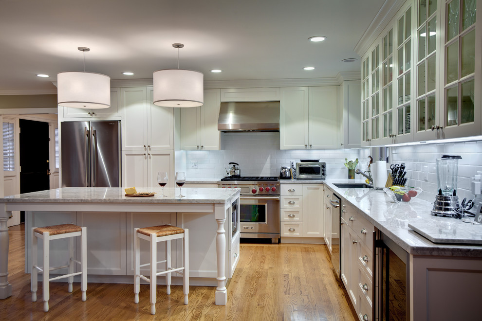 サンフランシスコにあるトラディショナルスタイルのおしゃれなL型キッチン (シェーカースタイル扉のキャビネット、シルバーの調理設備、サブウェイタイルのキッチンパネル、白いキャビネット、白いキッチンパネル、アンダーカウンターシンク) の写真