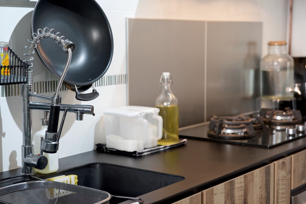 Immagine di una cucina industriale con lavello a doppia vasca, ante lisce, ante in legno scuro e paraspruzzi grigio