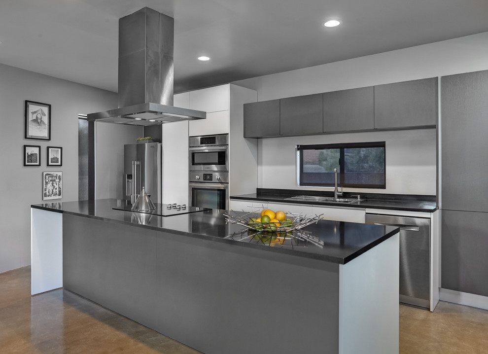 Inspiration for a small modern galley kitchen/diner in Phoenix with a built-in sink, flat-panel cabinets, grey cabinets, engineered stone countertops, black splashback, stainless steel appliances, concrete flooring, an island, grey floors and grey worktops.