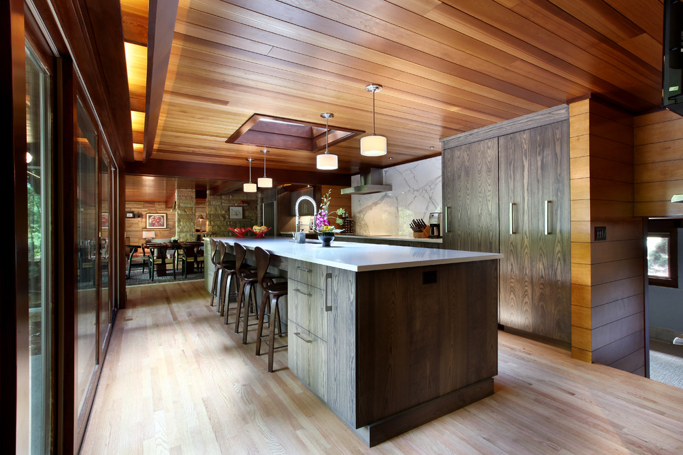 Foto på ett stort rustikt kök, med en undermonterad diskho, släta luckor, skåp i mörkt trä, grått stänkskydd, stänkskydd i marmor, integrerade vitvaror, ljust trägolv, en köksö och brunt golv